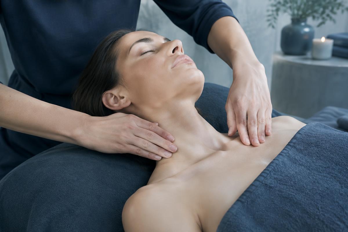 Therapist performing light lymphatic drainage along a client's neck